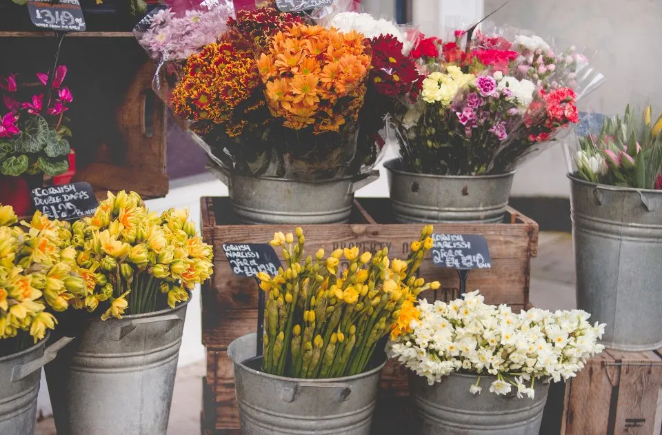 Cubos con ramos de flores de colores a la entrada de la tienda
